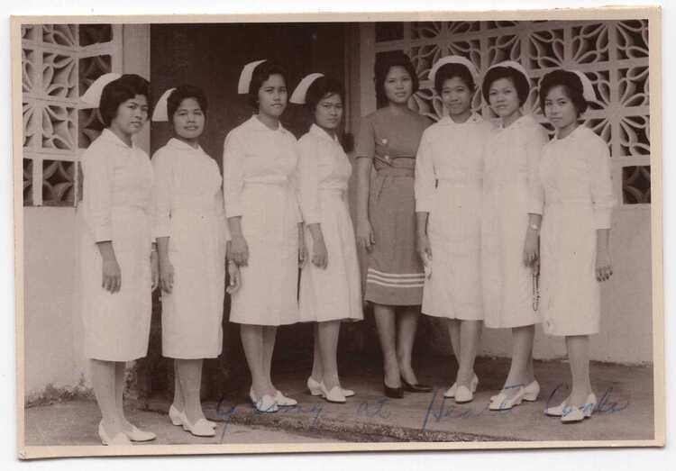 Historical photo of several Asian American nurses gathered oustide of a medical setting.